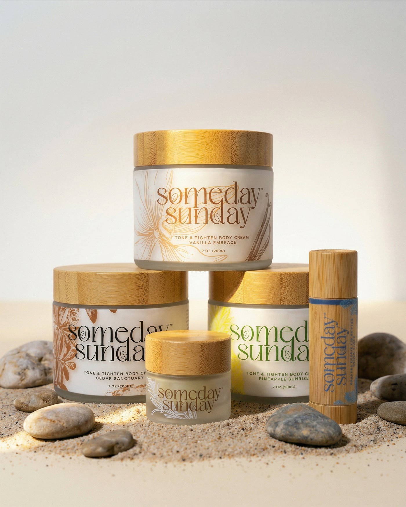 Someday Sunday body cream jars and lip butter sticks arranged on sand for a build your own duo.