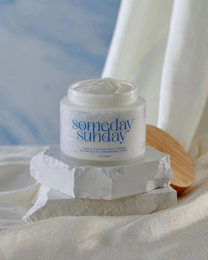 Someday Sunday Clean Slate body cream, fragrance-free, on pale stone.