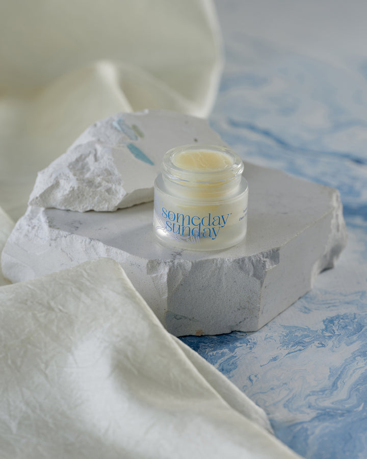 Someday Sunday Clean Slate lip butter jar, fragrance-free, on pale stone.